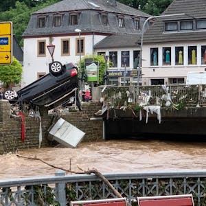 Am Morgen des 15. Juli 2021 zeigt sich das Ausmaß der Flutkatastrophe. In Gemünd hängt ein schwarzer SUV kopfüber auf dem Geländer an der Olef.