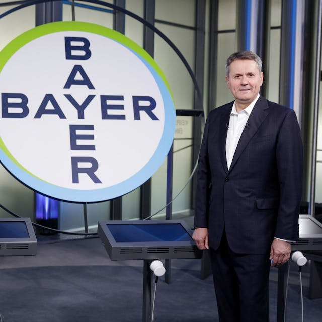 Norbert Winkeljohann steht neben dem Bayer-Logo