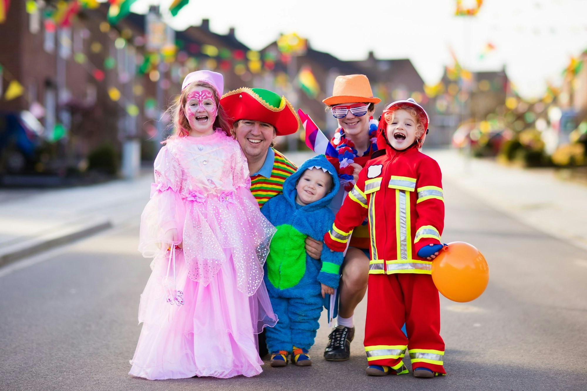 Kids and parents on Halloween trick or treat. Family in Halloween costumes with candy bags walking in decorated street trick or treating. Baby and preschooler celebrating carnival. Child costume.