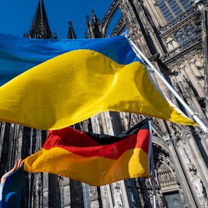 Eine ukrainische und eine deutsche Flagge wehen vor dem Kölner Dom.