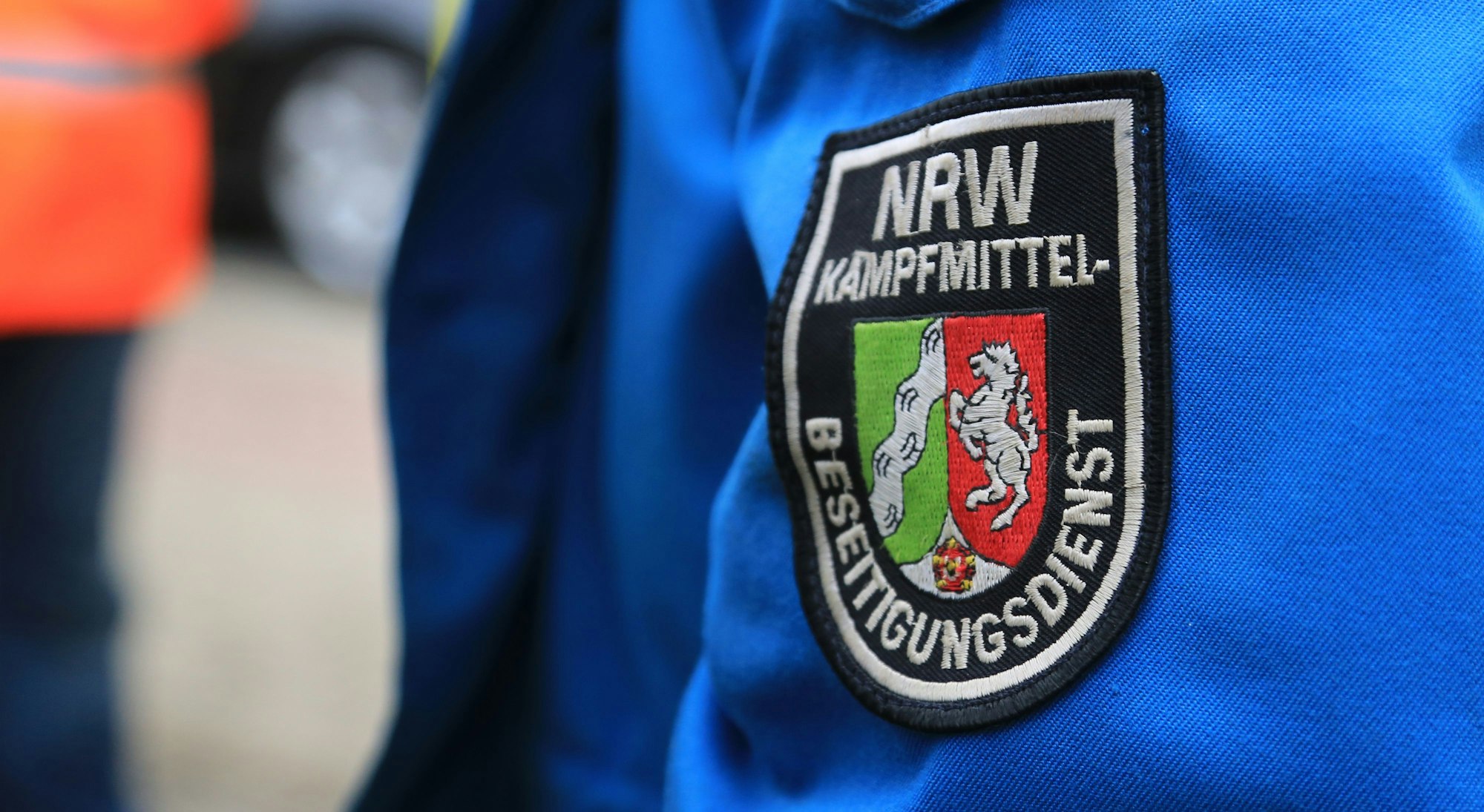 Ein Wappen mit der Aufschrift „NRW-Kampfmittel-Beseitigungsdienst“ ist auf einer Jacke aufgenäht.