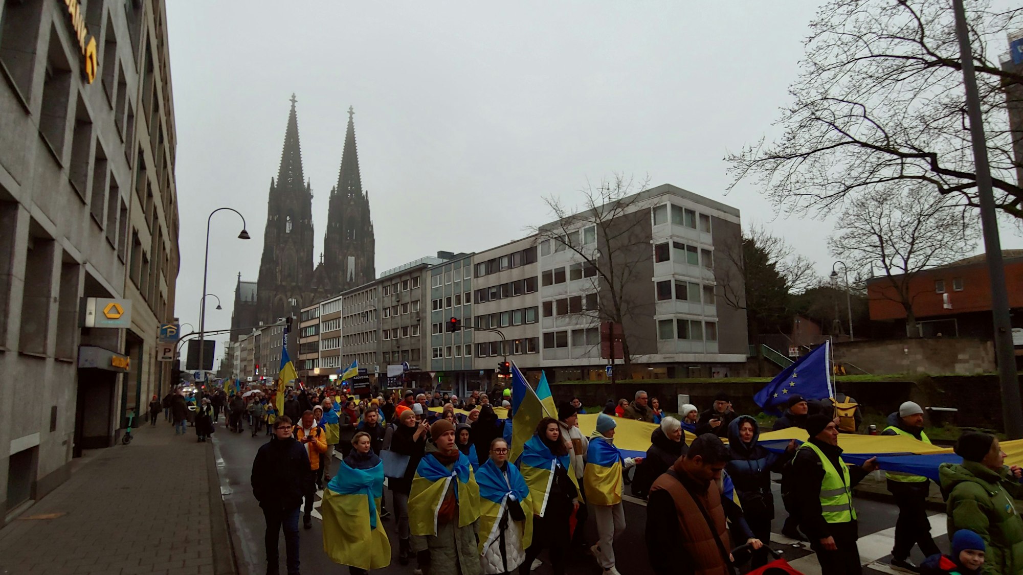 Die Demo zieht mit einer riesigen Ukraine-Flagge durch Köln.