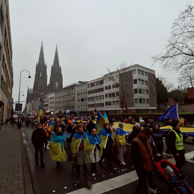 Die Demo zieht mit einer riesigen Ukraine-Flagge durch Köln.