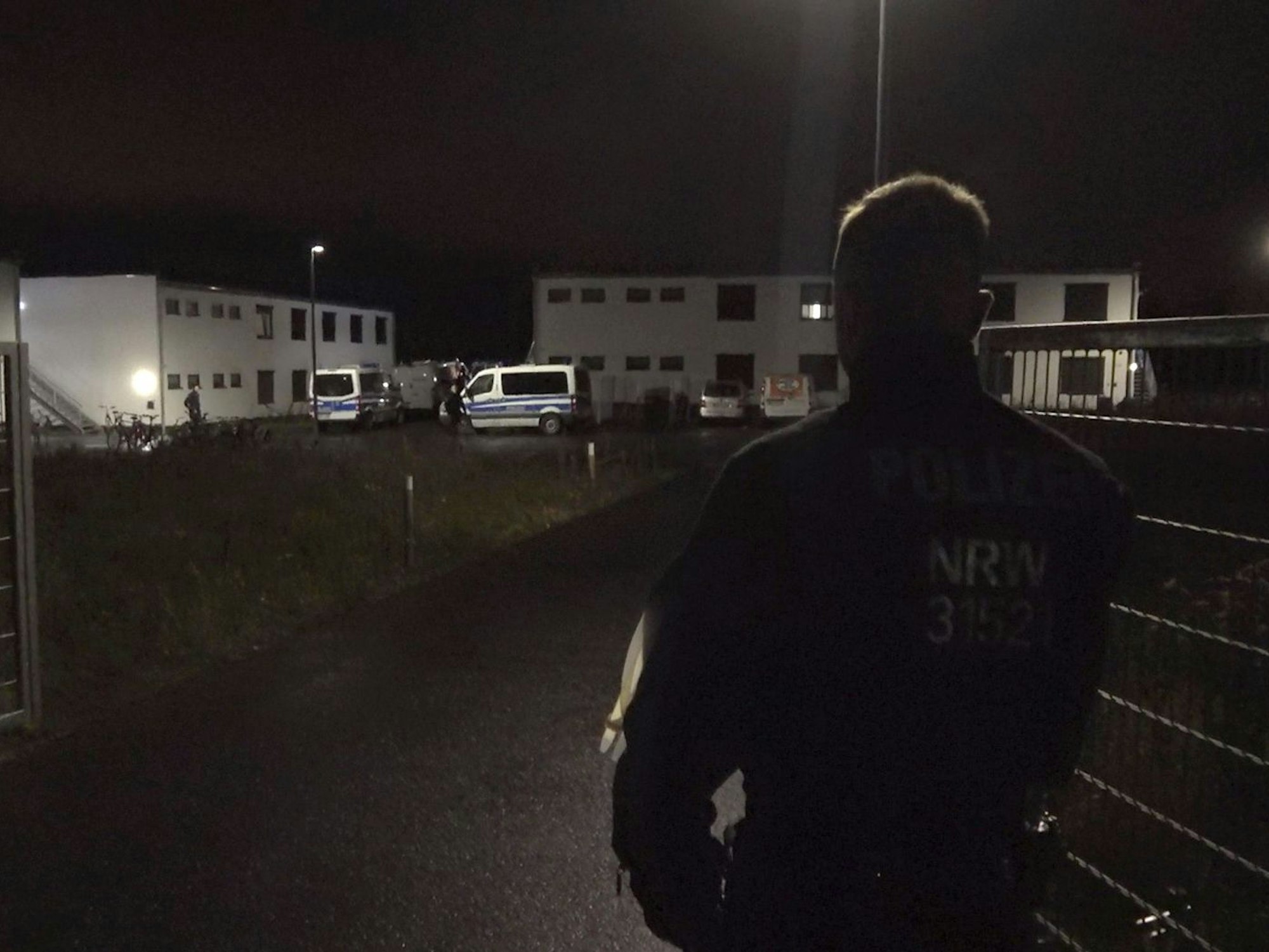 Ein Polizist steht am Tor zu einer Flüchtlingsunterkunft in Sankt Augustin. Eine vermisste Jugendliche ist am Sonntagabend tot in der Unterkunft gefunden worden.