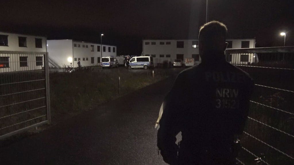Ein Polizist steht am Tor zu einer Flüchtlingsunterkunft in Sankt Augustin. Eine vermisste Jugendliche ist am Sonntagabend tot in der Unterkunft gefunden worden.&nbsp;