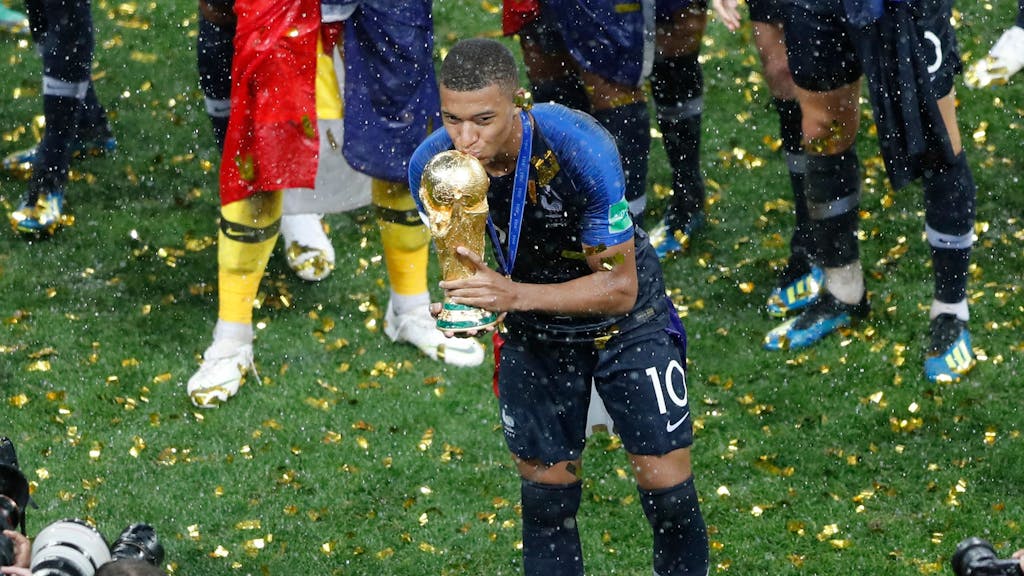 Kylian Mbappé küsst 2018 vor Fotografen den WM-Pokal.