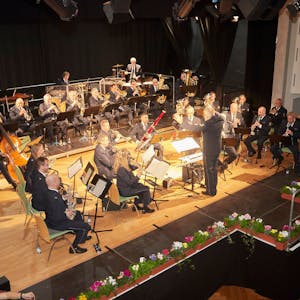 Das Landespolizeiorchester auf der Bühne im Gemünder Kursaal, die mit Blumen dekoriert ist.