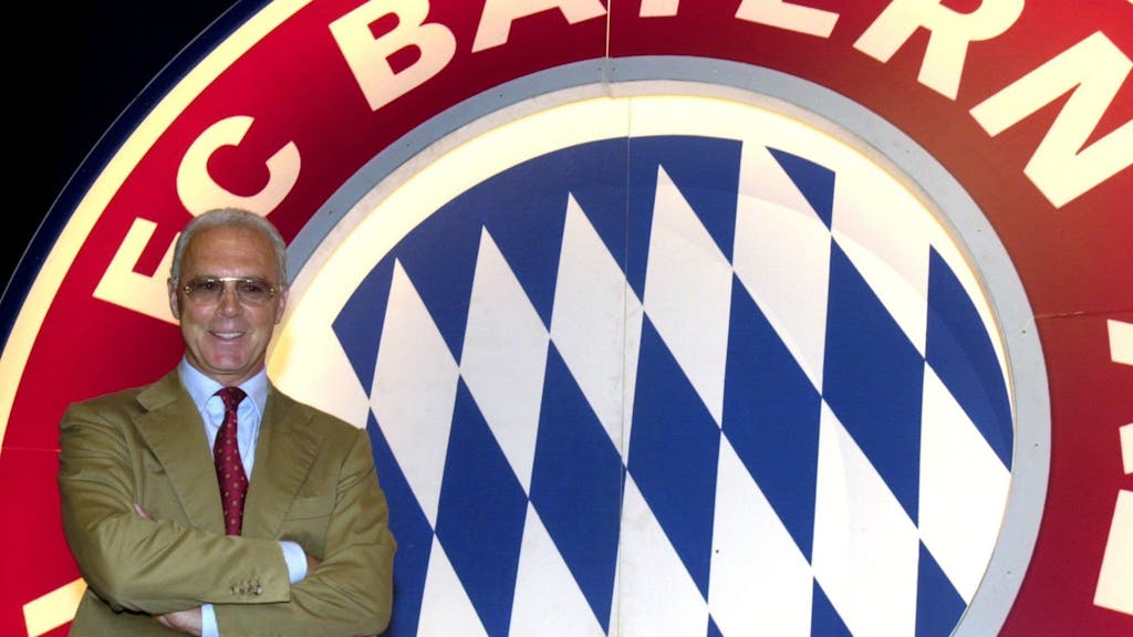 Franz Beckenbauer vor dem Logo des FC Bayern München.&nbsp;