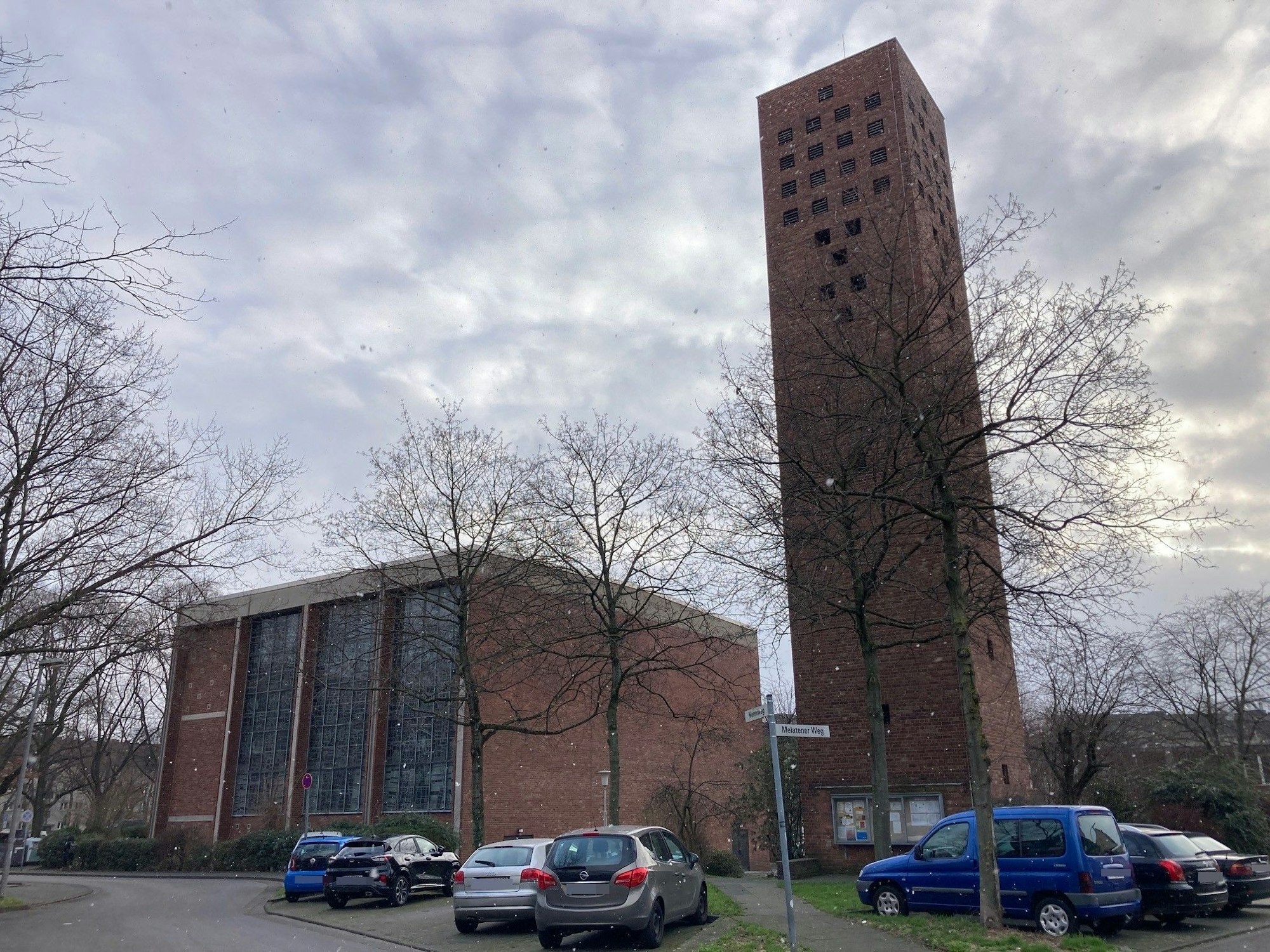 Vor einem fünfeckigen Ein Kirchengebäude mit separatem Turm parken Autos.