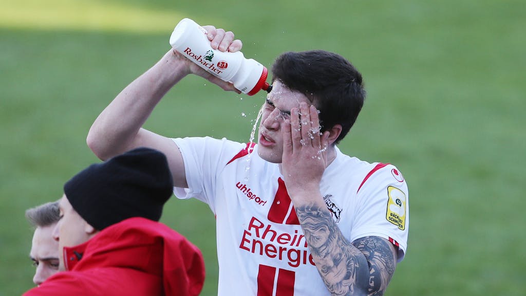 Joao Queiros wäscht sich das Gesicht mit Wasser aus einer Trinkflasche.