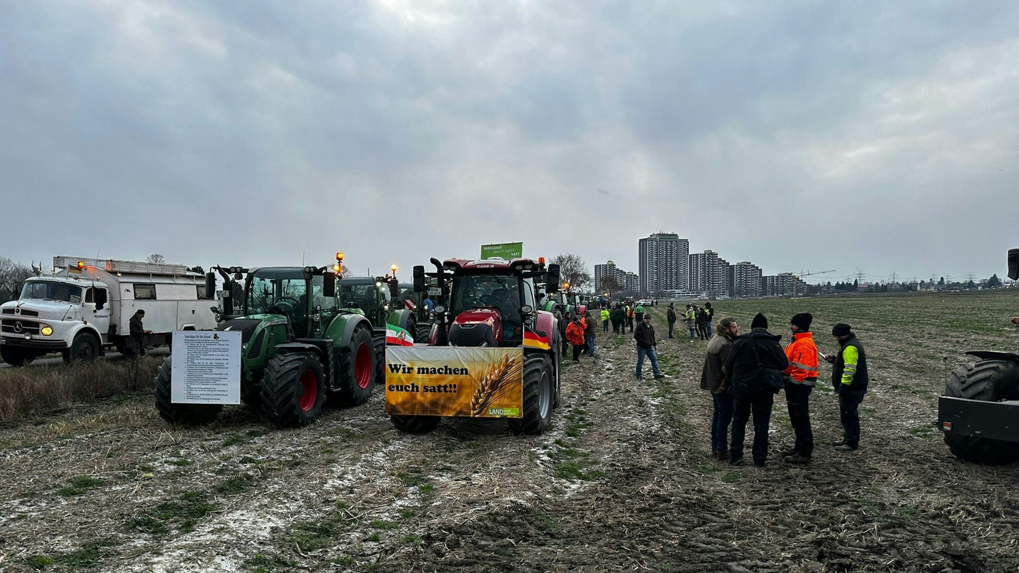 Dutzende Traktoren und Menschen stehen auf einem Feld in Köln.