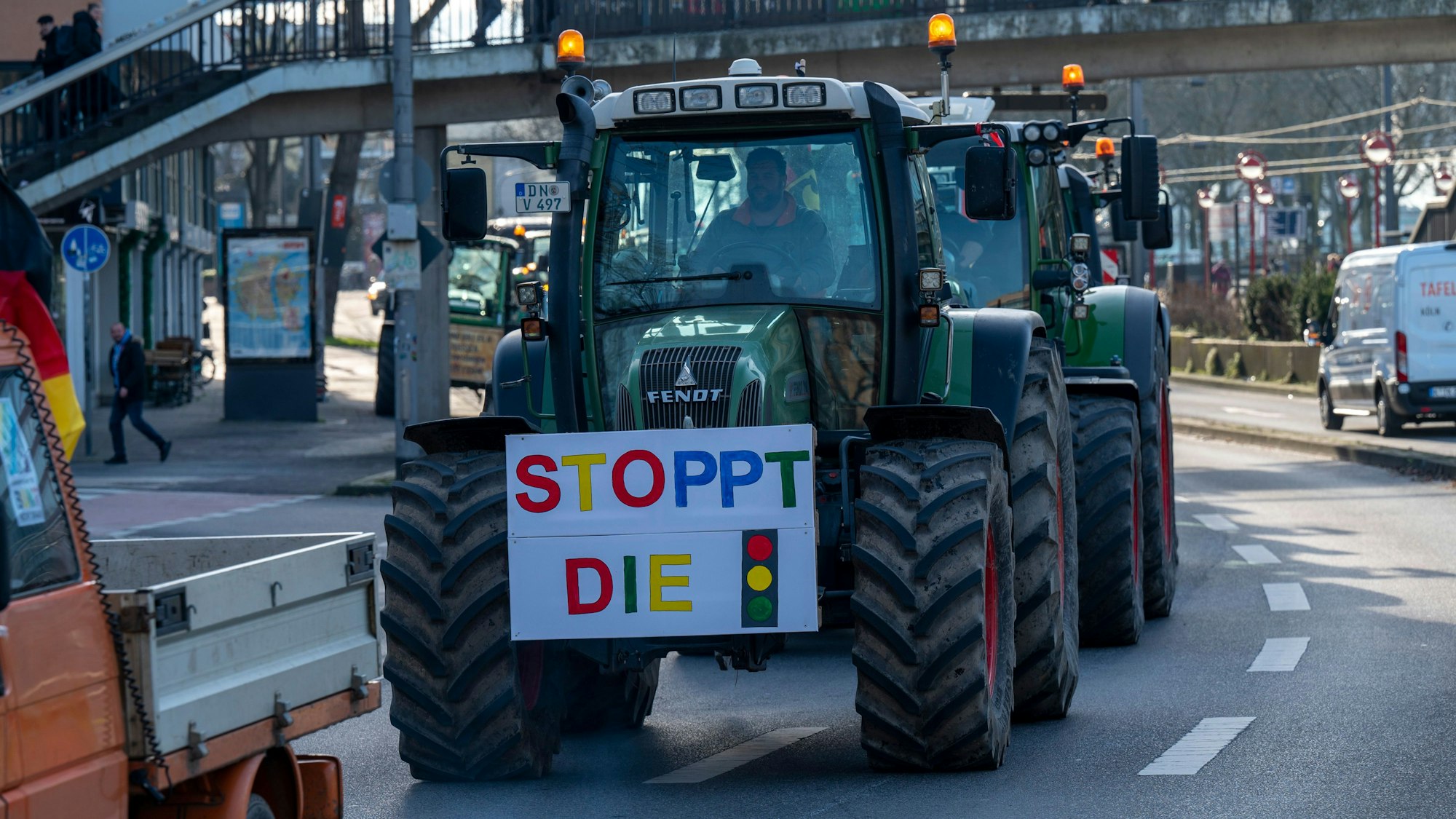 Ein Traktor fährt während einer Kundgebung mit einem großen Schild über eine Straße.