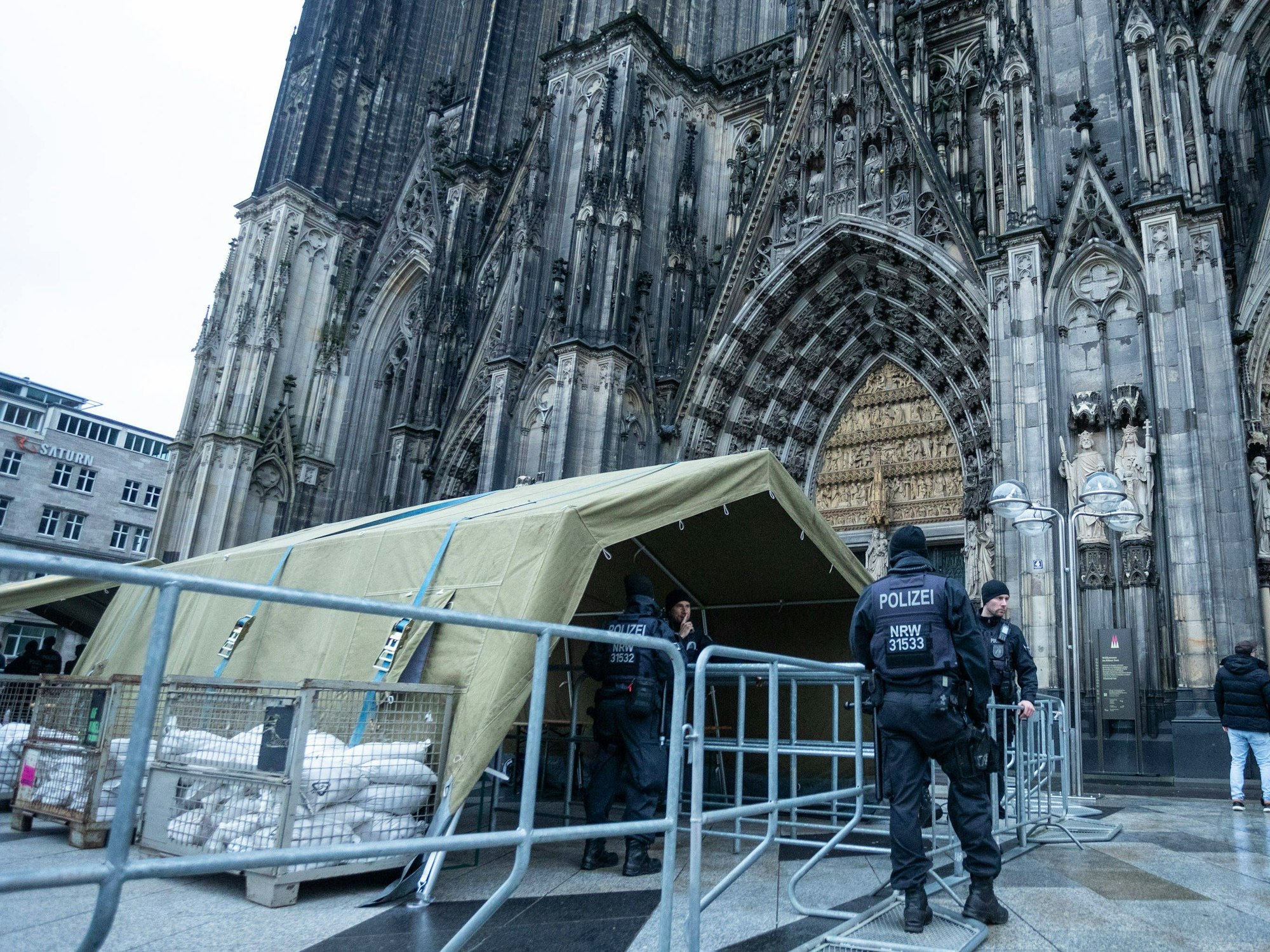 Vor dem Kölner Dom steht ein Zelt, davor zwei Polizisten.