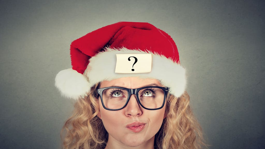 Eine junge Frau mit Santa Claus-Mütze und fragendem Gesichtsausdruck