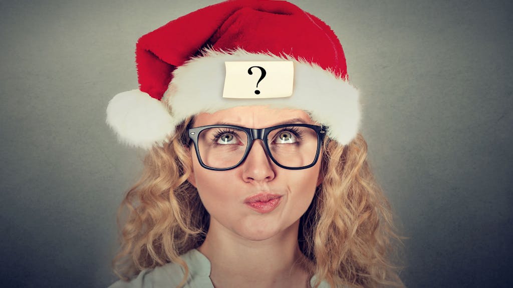 Eine junge Frau mit Santa Claus-Mütze und fragendem Gesichtsausdruck