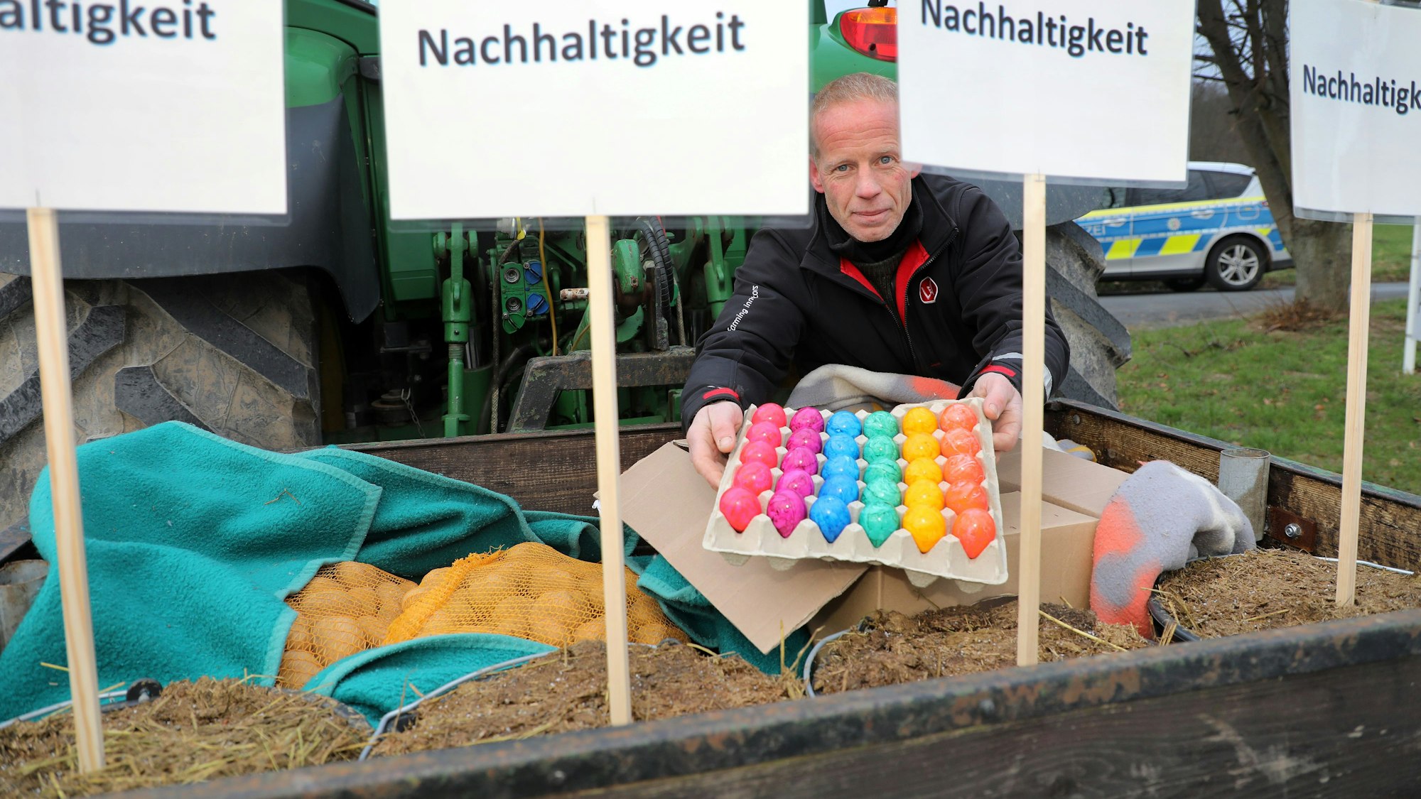 Landwirt Markus Freihoff zeigt Eier und Kartoffeln auf der Ladekiste seines Traktors.