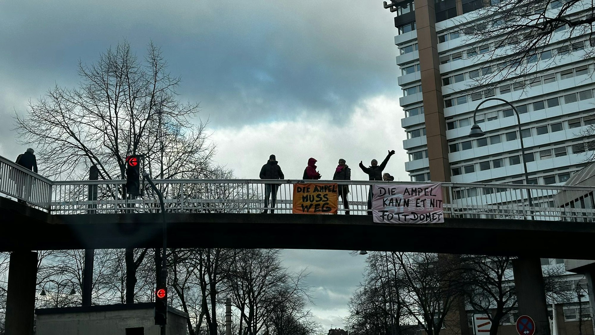 Menschen auf einer Brücke zeigen Plakate.