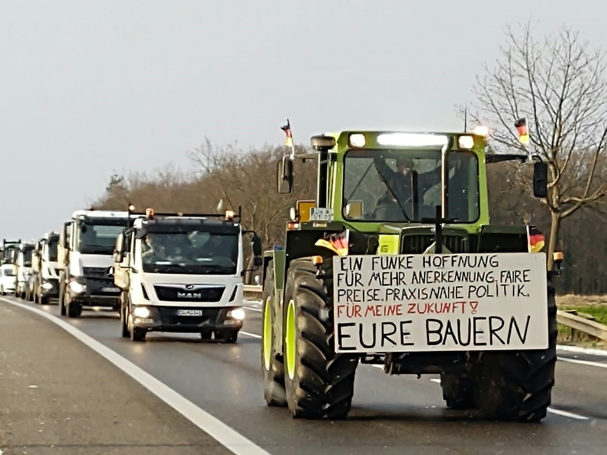 Ein Traktor und Fahrzeuge im Stau. Auf dem Traktor ein Schild mit der Aufschrift: „Ein Funke Hoffnung für mehr Anerkennung, faire Preise, praxisnahe Politik. Für meine Zukunft! Eure Bauern“.