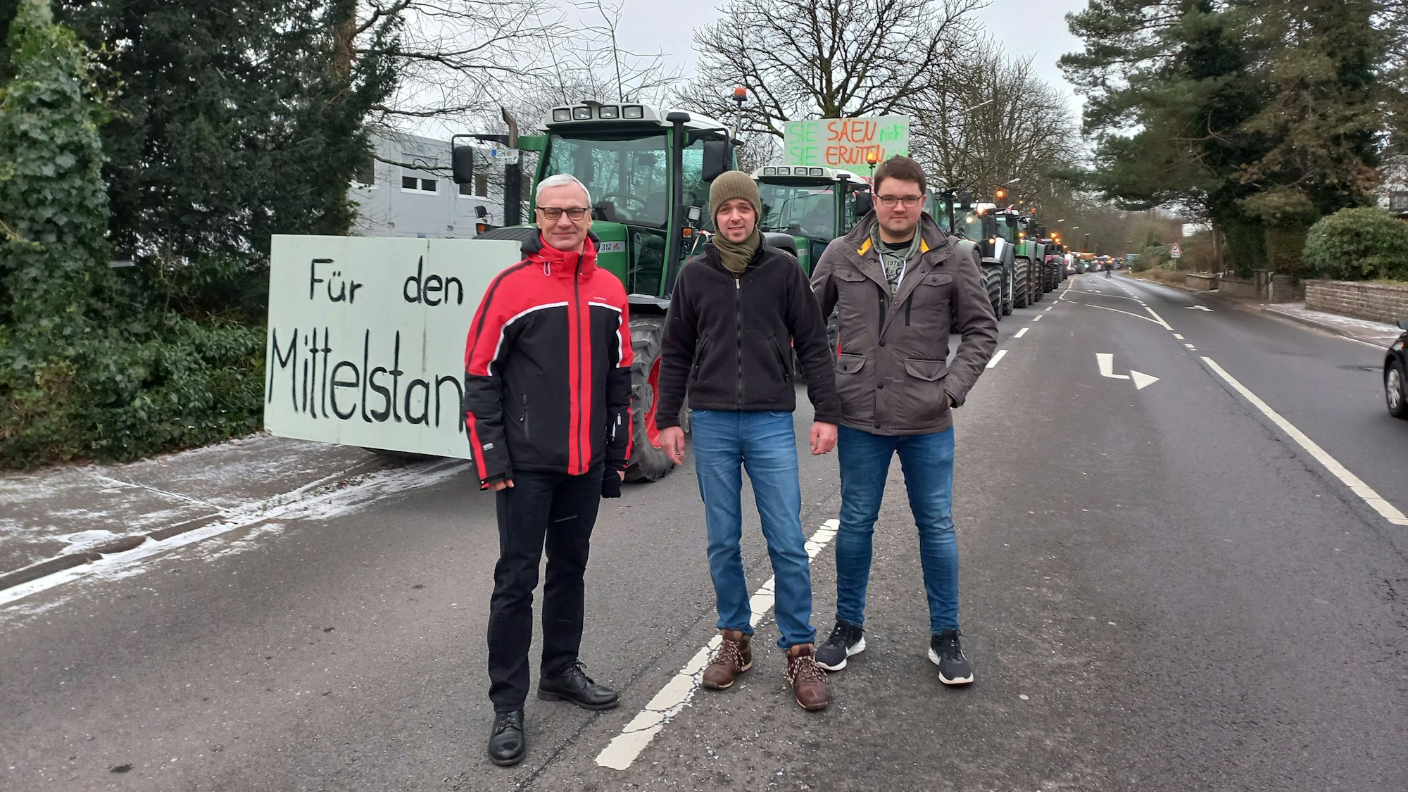 Bauernprotest in Lindlar: (v.l.) Lindlars Bürgermeister Dr. Georg Ludwig und die Organisatoren David Höller und Martin Gräf stehen vor einem Traktor mit Protestschild.