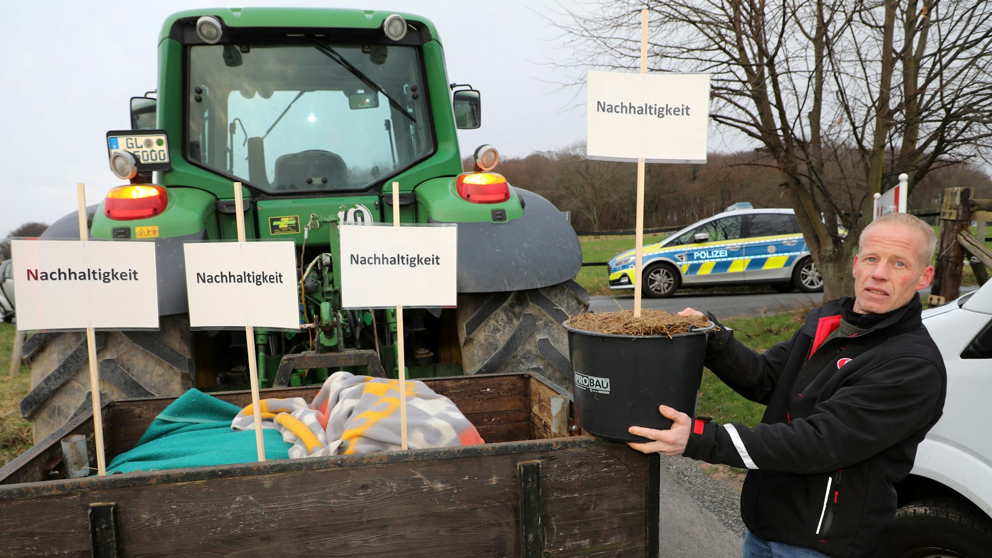 Landwirt Markus Freihoff aus Kürten zeigt Mistkübel mit Schildern auf denen „Nachhaltigkeit“ steht.
