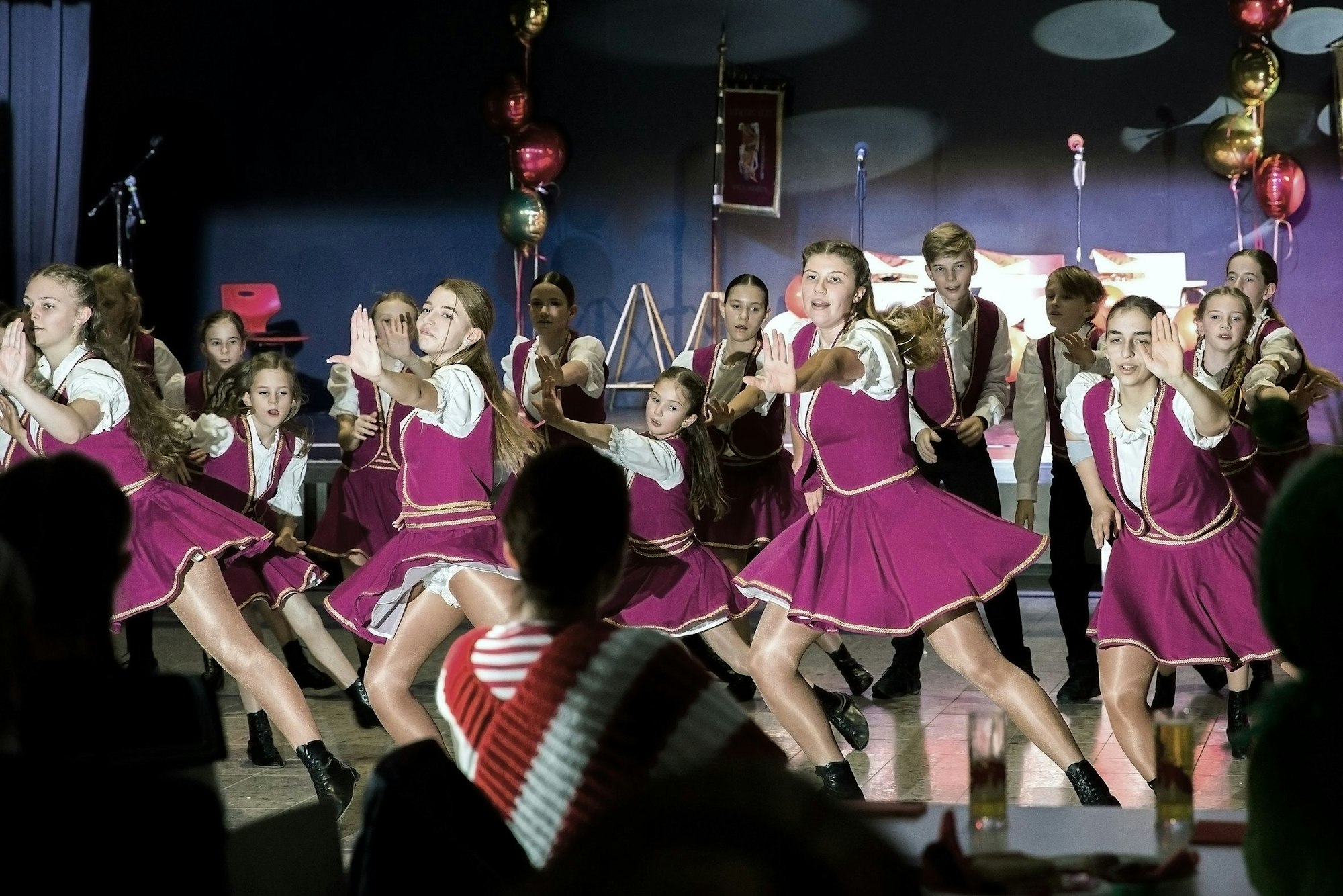 Mädchen in lila Röcken tanzen auf einer Bühne.