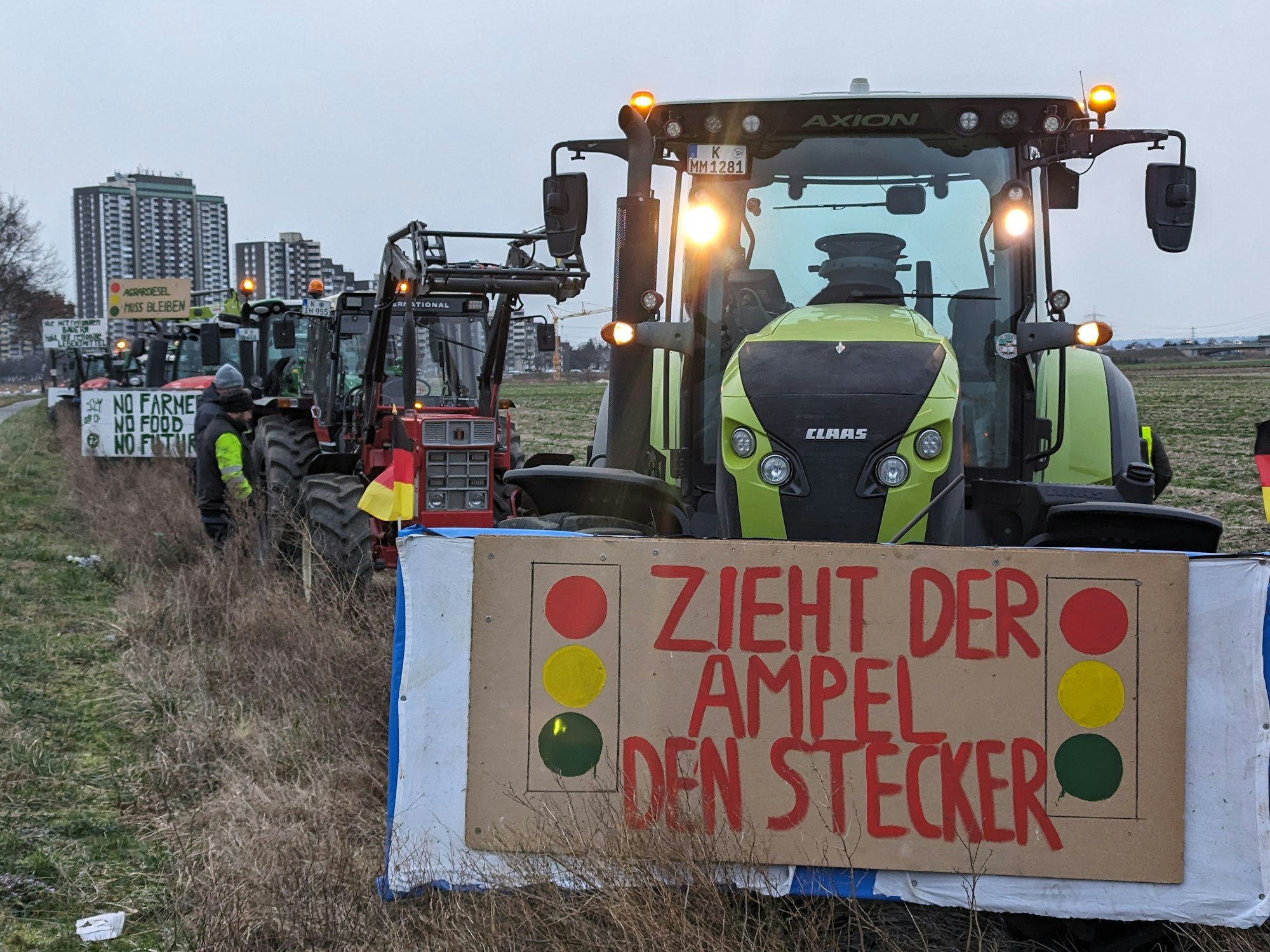 Traktoren in Kolonne. Ein Schild mit der Aufschrift: „Zieht der Ampel den Stecker“.
