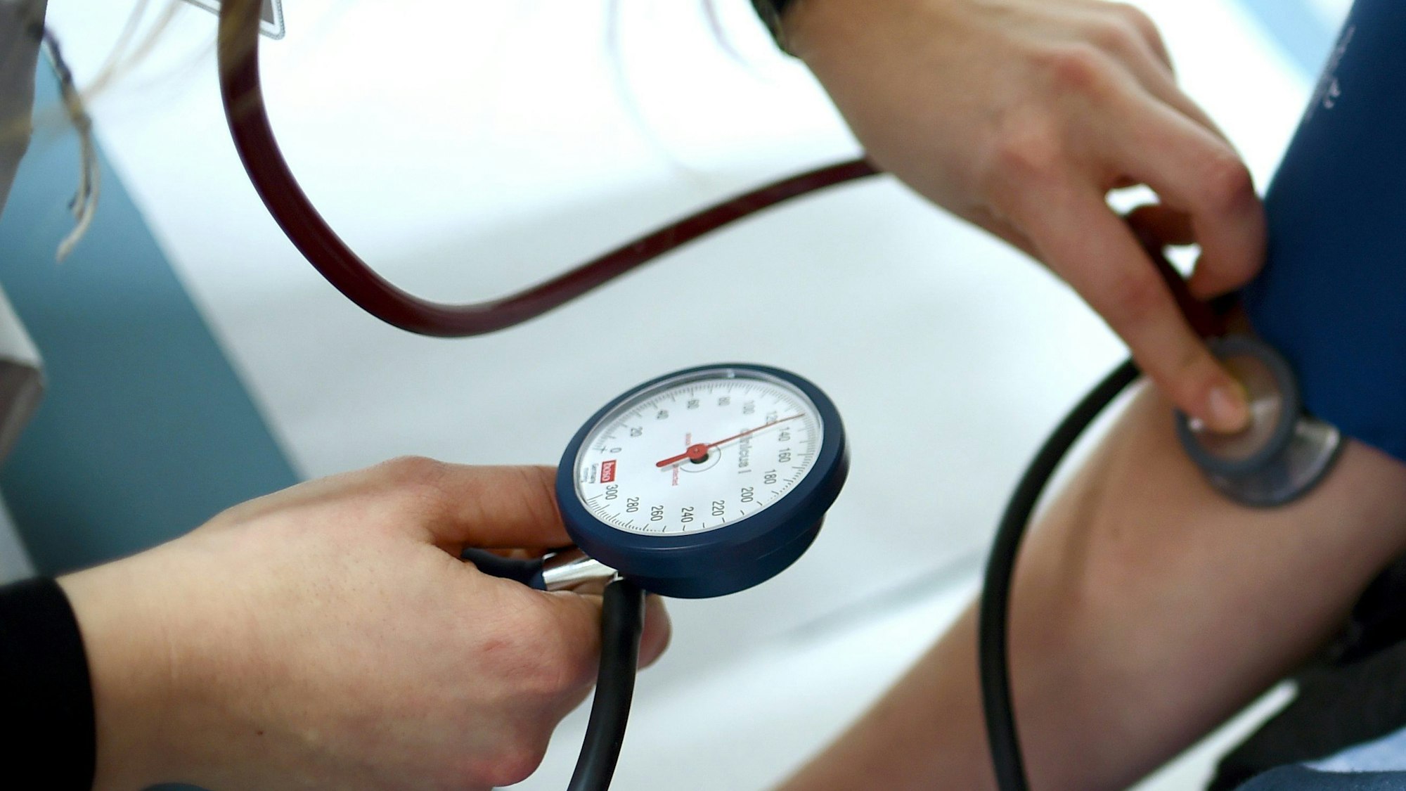 Einem Menschen wird in einer Arztpraxis der Bluthochdruck gemessen. Aus Protest gegen die Gesundheitspolitik von Bundesminister Lauterbach haben Ärzteverbände dazu aufgerufen, Hausarzt- und Facharztpraxen bundesweit zwischen den Jahren geschlossen zu halten.