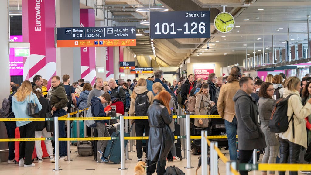Menschen warten am Check-in am Flughafen Köln/Bonn in einer langen Schlange.