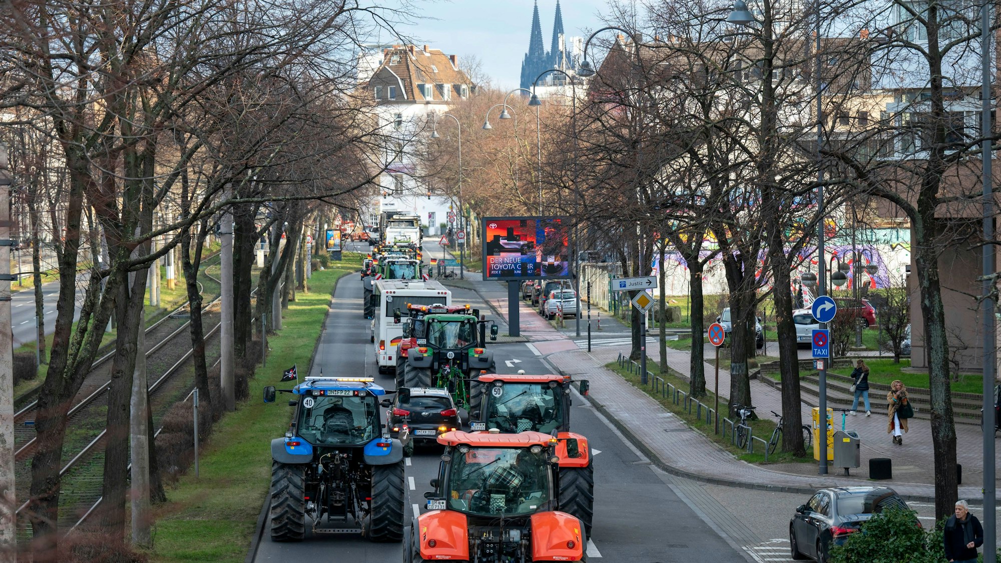 Traktoren fahren eine Straße in Köln entlang, im Hintergrund ist der Dom zu sehen.
