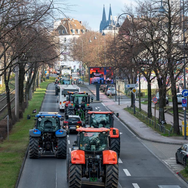 Traktoren fahren eine Straße in Köln entlang, im Hintergrund ist der Dom zu sehen.