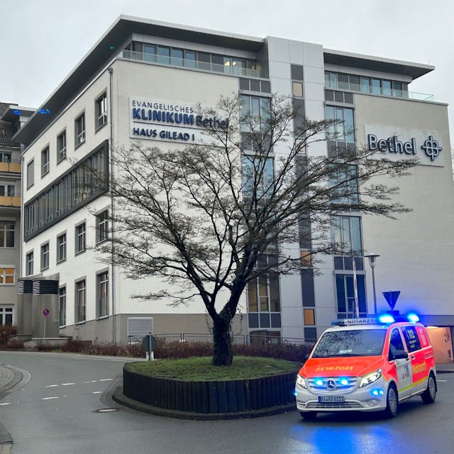 Blick auf das Gebäude des Klinikums Bethel in Bielefeld. Ein Rettungswagen mit Blaulicht fährt vorbei.&nbsp;