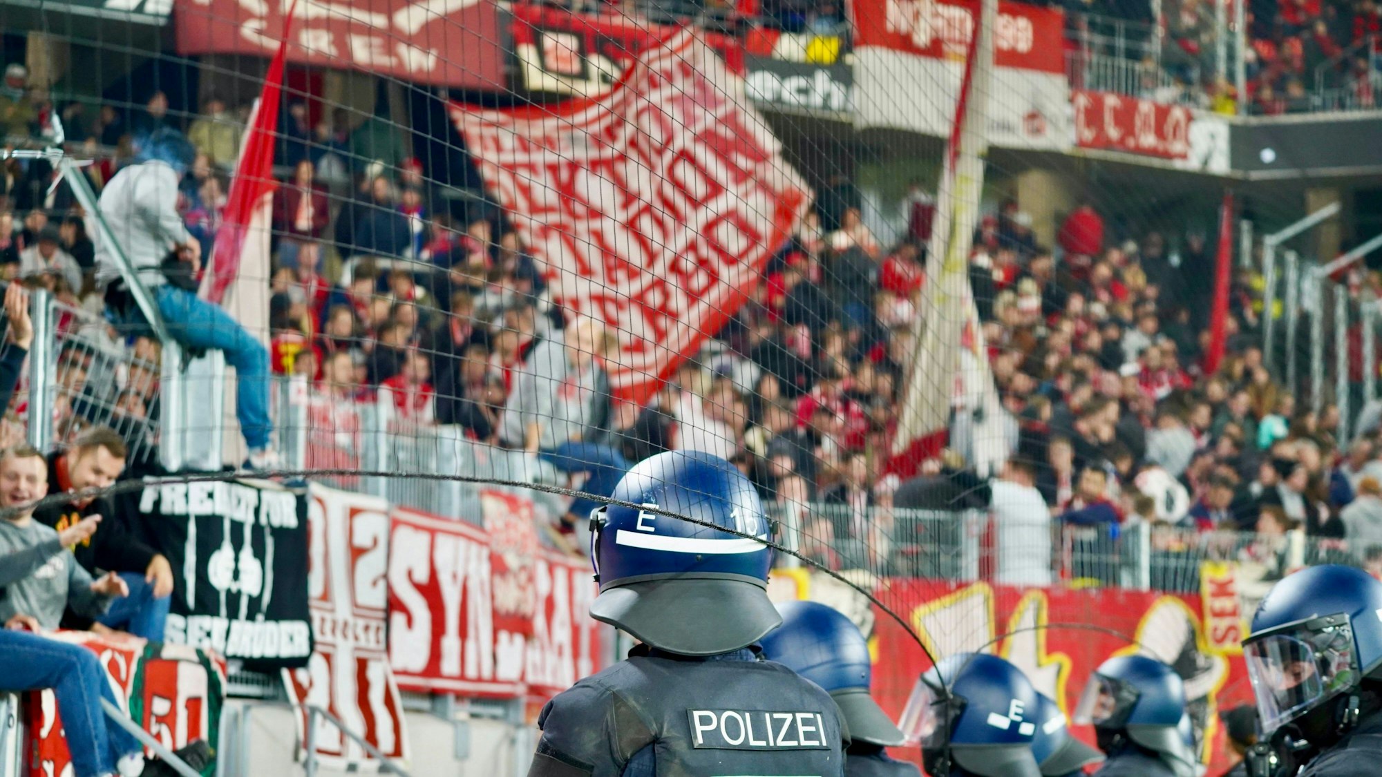 Polizisten blicken beim Auswärtsspiel des 1. FC Köln in Freiburg auf den Kölner Fan-Block. (Archivbild)
