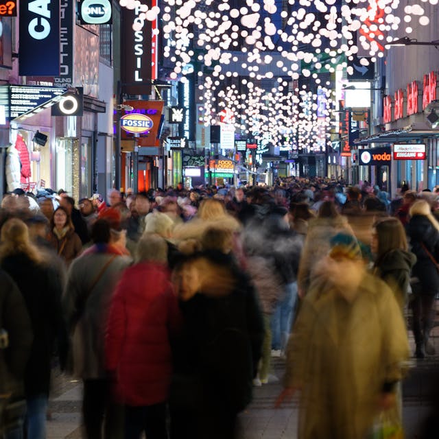 Einkäufer gehen durch eine mit&nbsp;Weihnachtslichtern geschmückte Einkaufsstraße