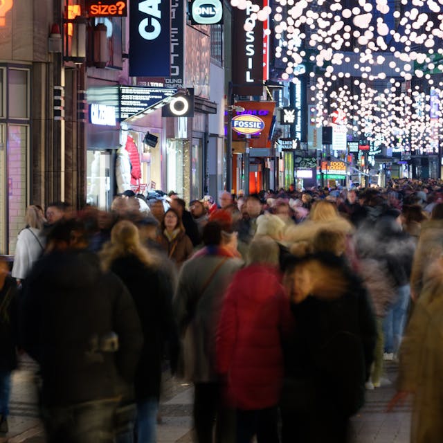 Einkäufer gehen durch eine mit&nbsp;Weihnachtslichtern geschmückte Einkaufsstraße