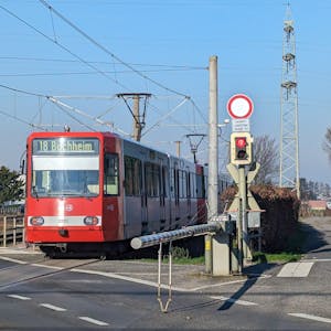 Eine Stadtbahn fährt in den Haltepunkt Fischenich ein, neben den Gleisen ein Wirtschaftsweg.