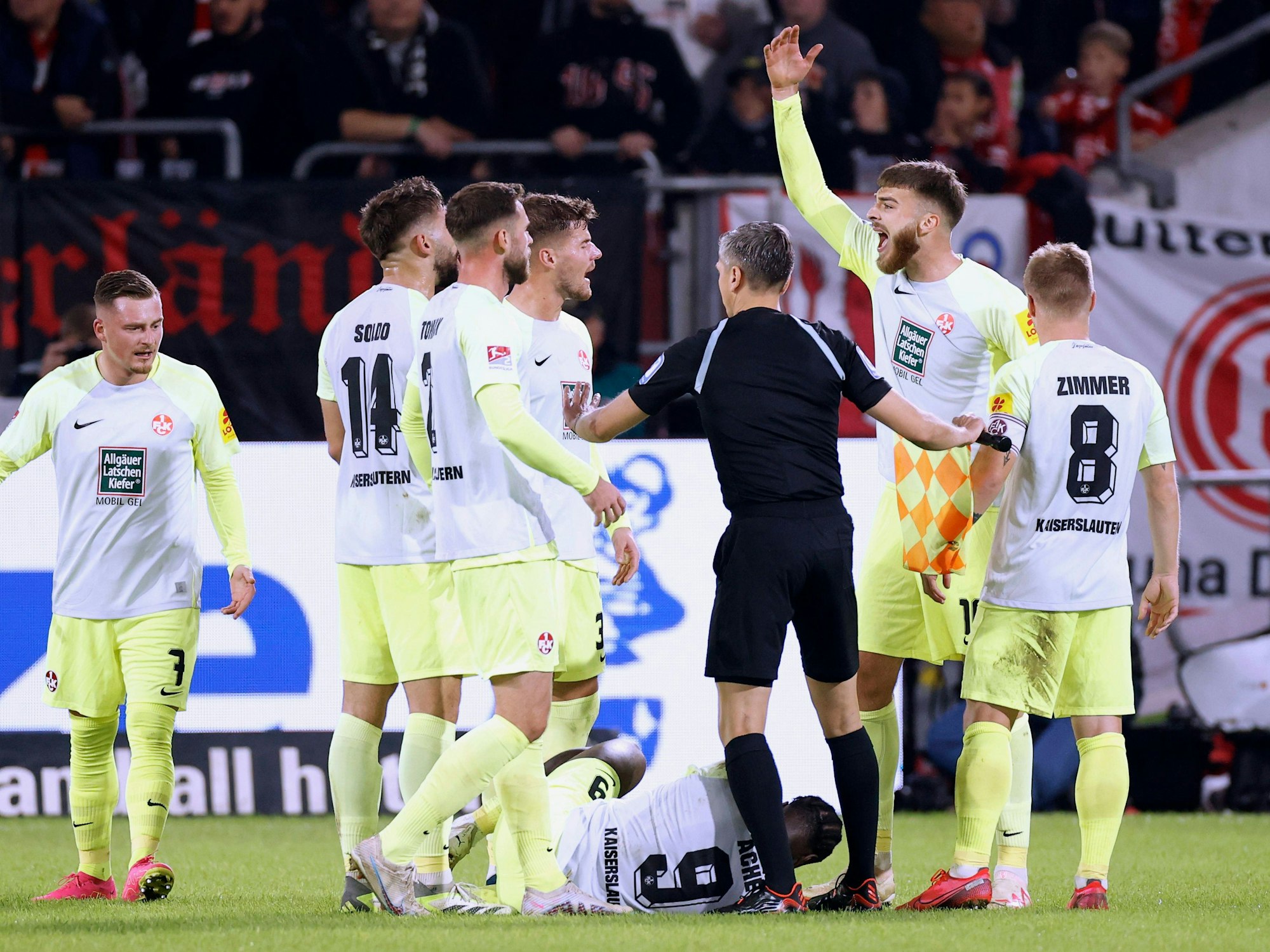 Stürmer Ragnar Ache vom 1. FC Kaiserslautern liegt beim Spiel in Düsseldorf am Boden, seine Teamkollegen und der Schiedsrichter bilden einen Kreis um ihn.
