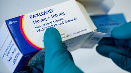 Ein Apotheker hält das Corona-Medikament Paxlovid in den Händen. Bundesweit soll es zu illegalem Weiterverkauf des Mittels gekommen sein. (Symbolbild)
