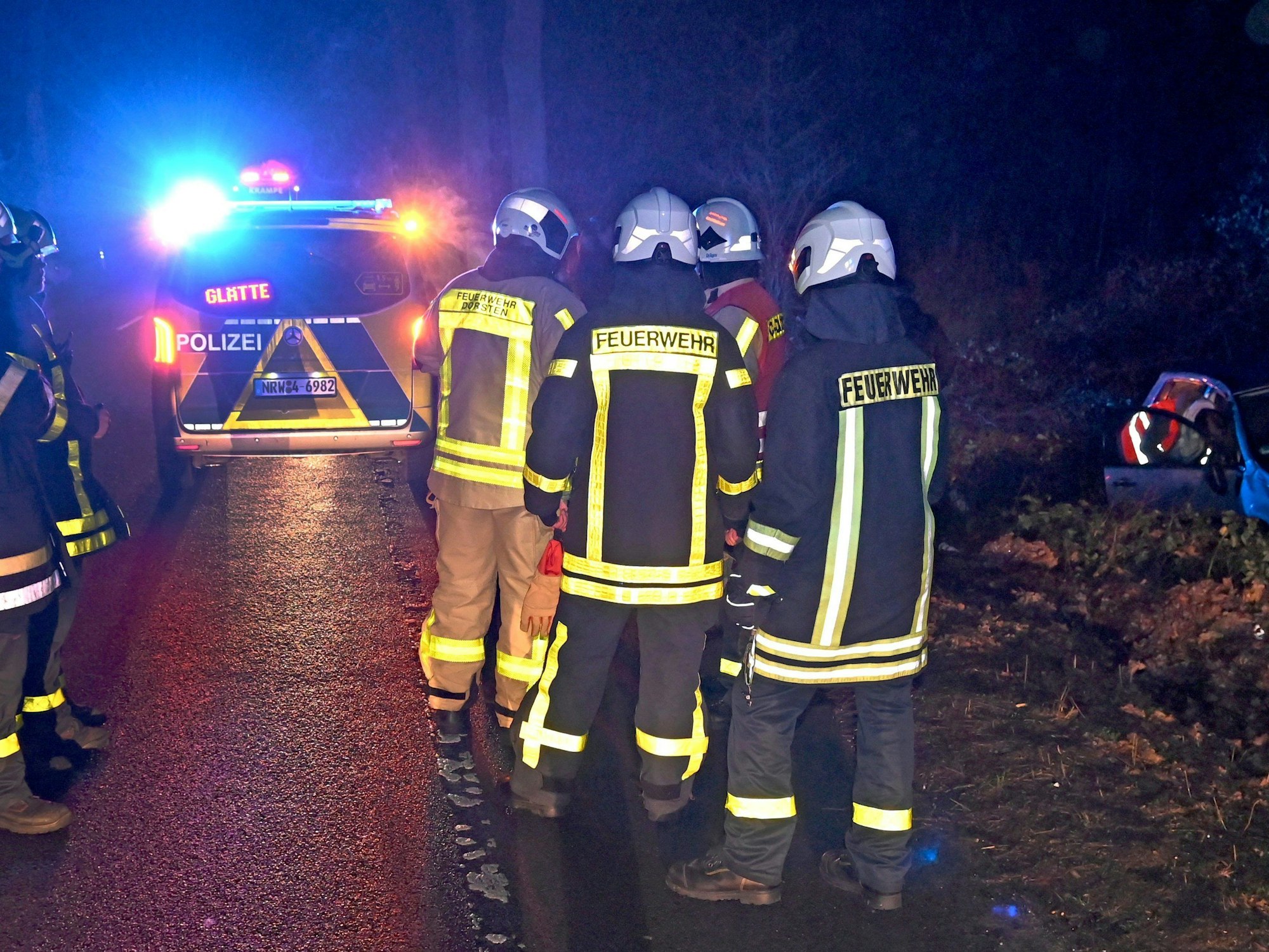 Einsatzkräfte der Feuerwehr stehen am Donnerstagabend (11. Januar) bei Dorsten auf der Bundesstraße 58 an der Unfallstelle mit einem verunfallten Pkw, der witterungsbedingt von der glatten Fahrbahn in den Straßengraben geraten war.