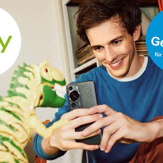 Junger Mann schießt mit dem Smartphone ein Bild von einem Spielzeug-Dinosaurier. Ebay Logo auf Bild.