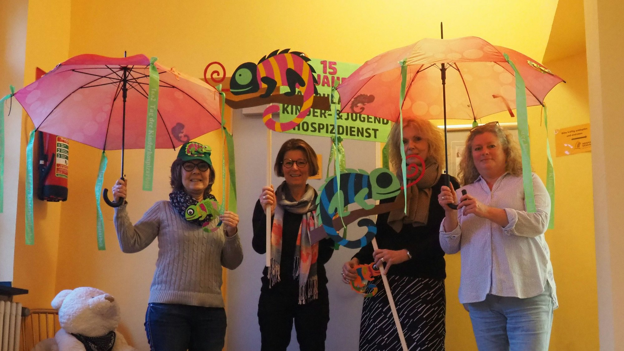 Vier Frauen zeigen bunte Regenschirmen und schillernde Chamäleons.