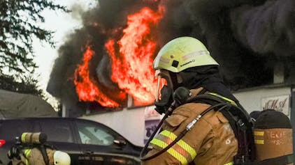 Feuerwehrleute kämpfen gegen einen Brand in einer Lagerhalle in Bergisch Gladbach.