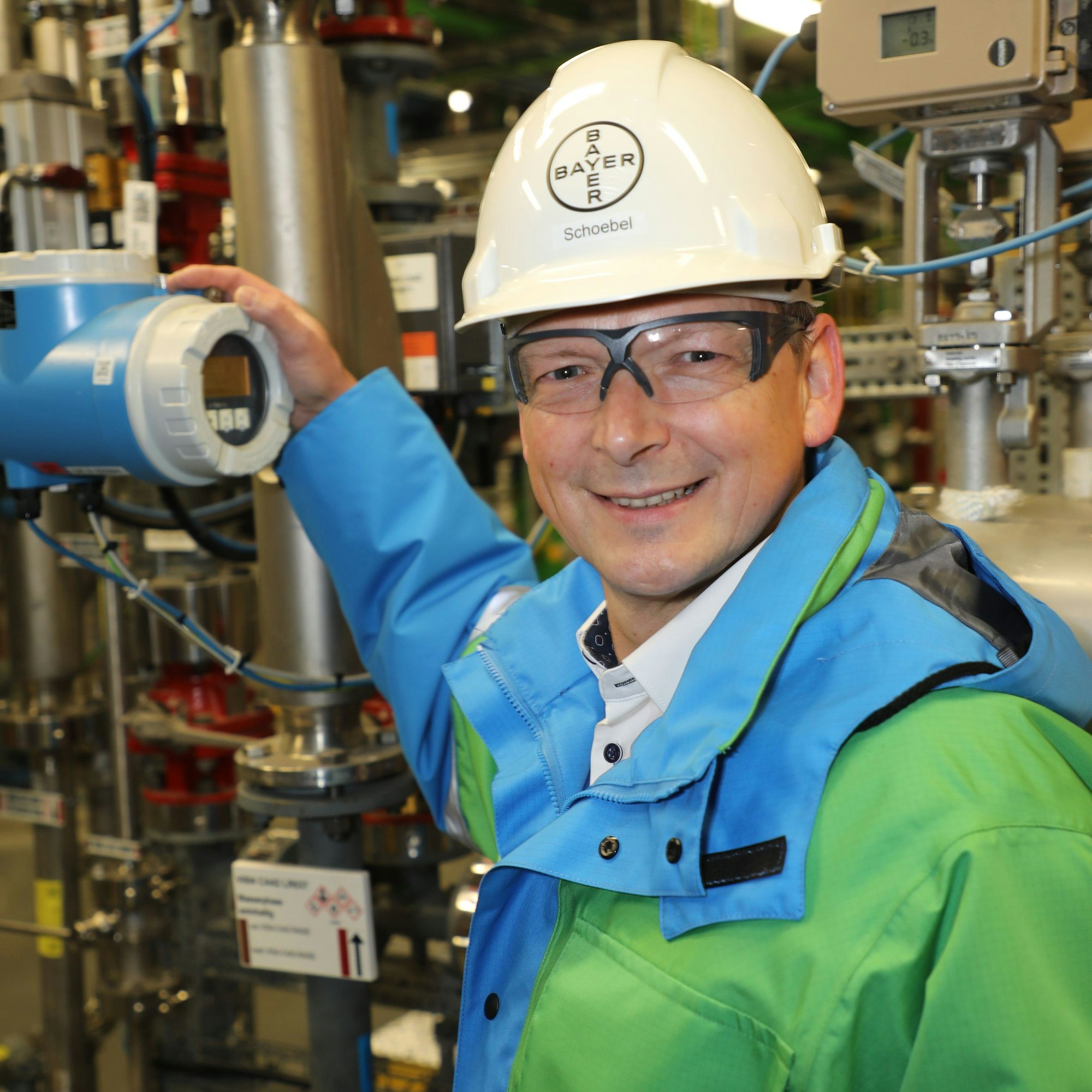 Gerd Schöbel arbeitet steht mit Helm an Messinstrumenten im Bayer-Werk Dormagen.