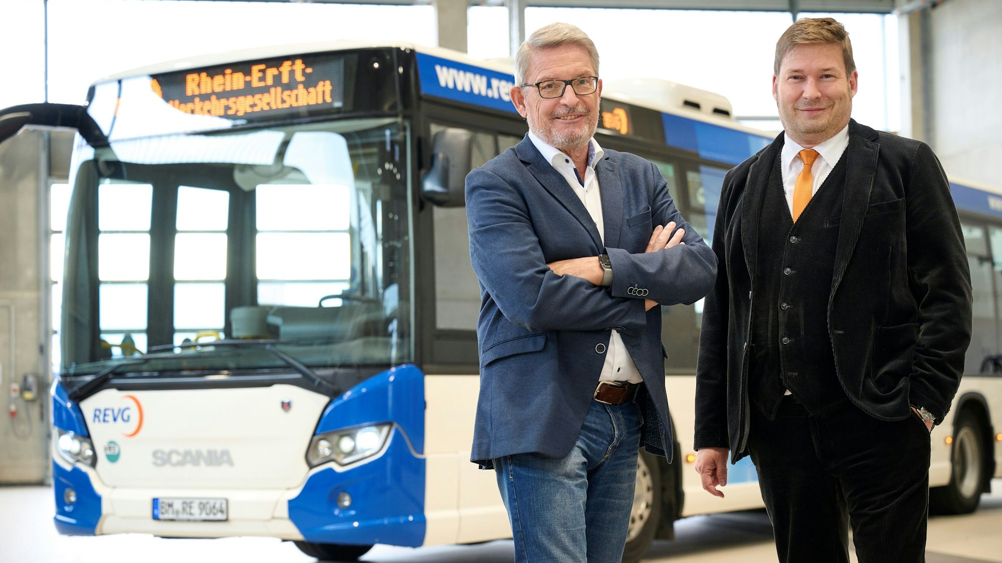 Die REVG-Geschäftsführer Walter Reinarz und Martin Gawrisch stehen vor einem blau-weißen Linienbus.