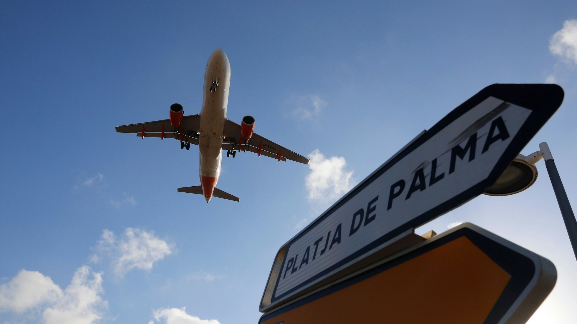 Ein Flugzeug überfliegt bei der Landung auf Mallorca ein Schild, das die Richtung nach Playa de Palma anzeigt.