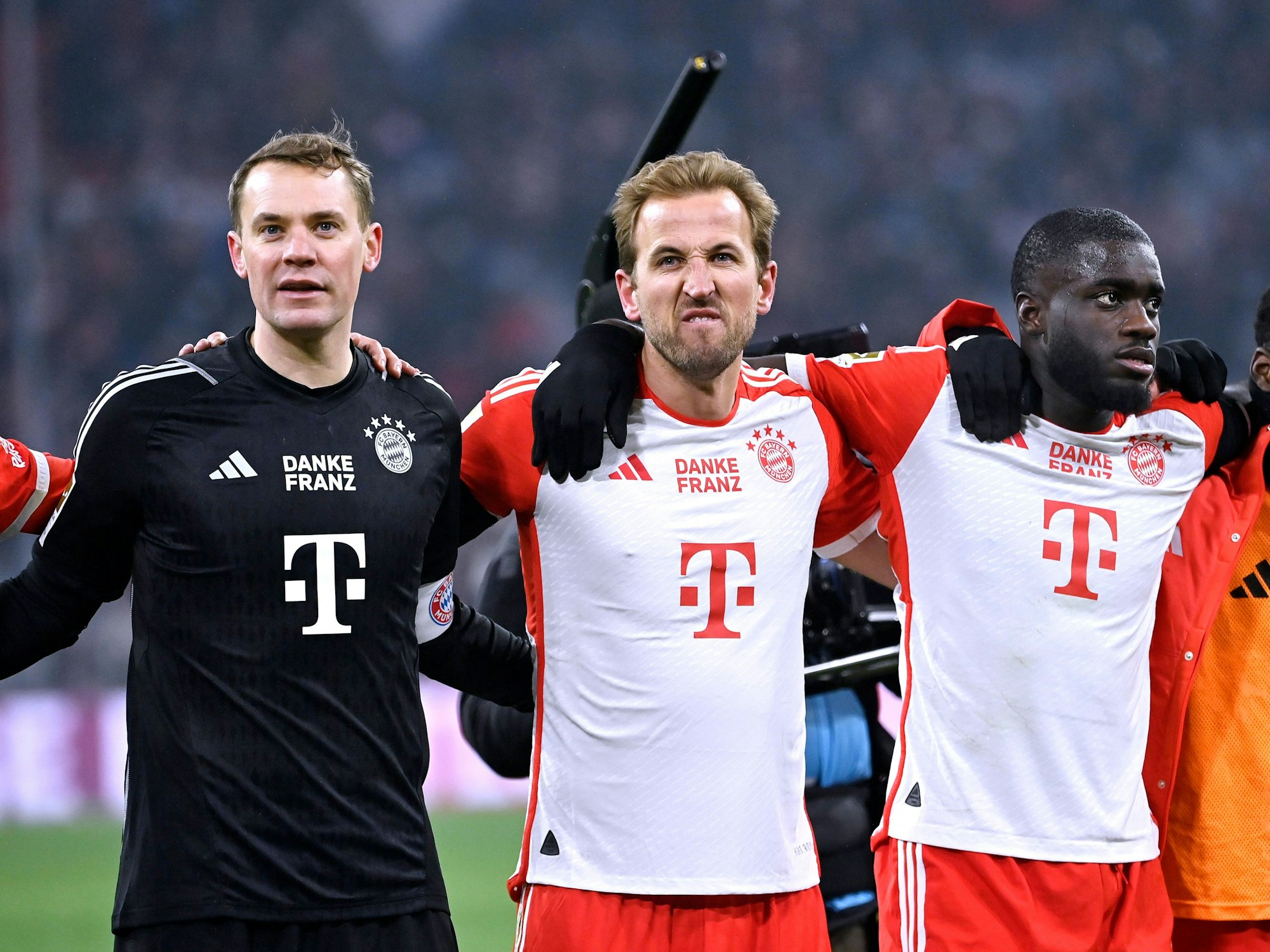 Manuel Neuer, Harry Kane und Dayot Upamecano jubeln Arm in Arm vor den Fans nach dem Spiel.