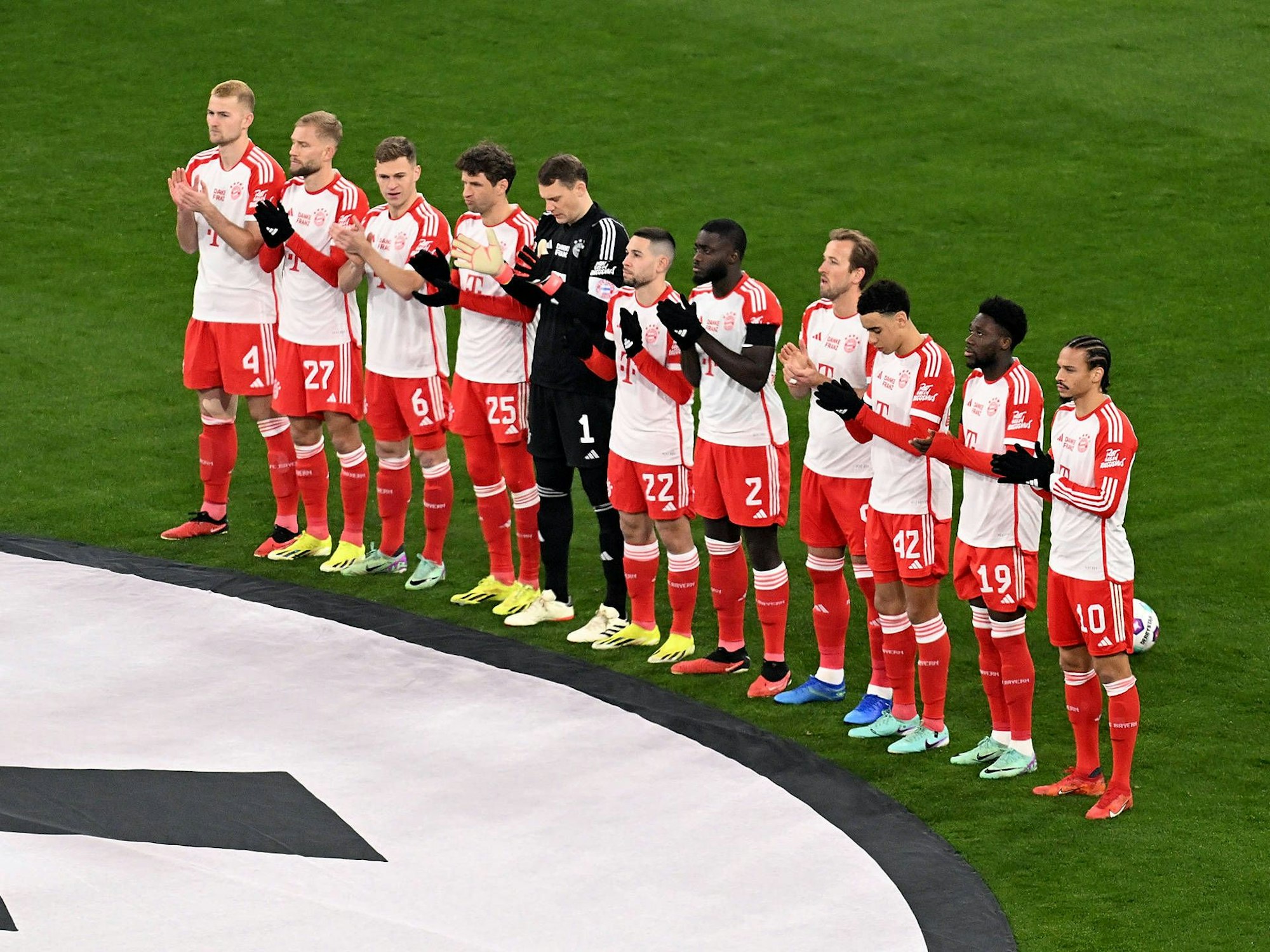 Die Spieler des FC Bayern stehen in einer Reihe und applaudieren.