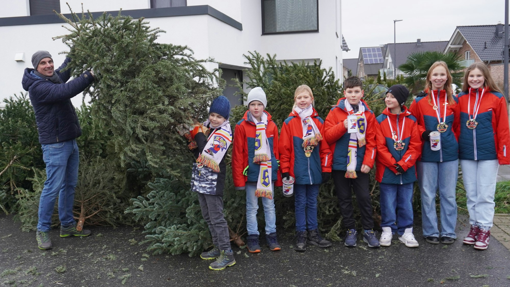 Zu sehen ist eine Gruppe von Kindern, die beim Sammeln der abgeschmückten Weihnachtsbäume halfen sowie einer der beteiligten Väter.
