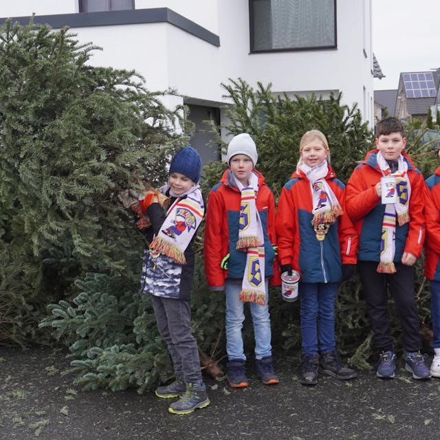 Zu sehen ist eine Gruppe von Kindern, die beim Sammeln der abgeschmückten Weihnachtsbäume halfen sowie einer der beteiligten Väter.