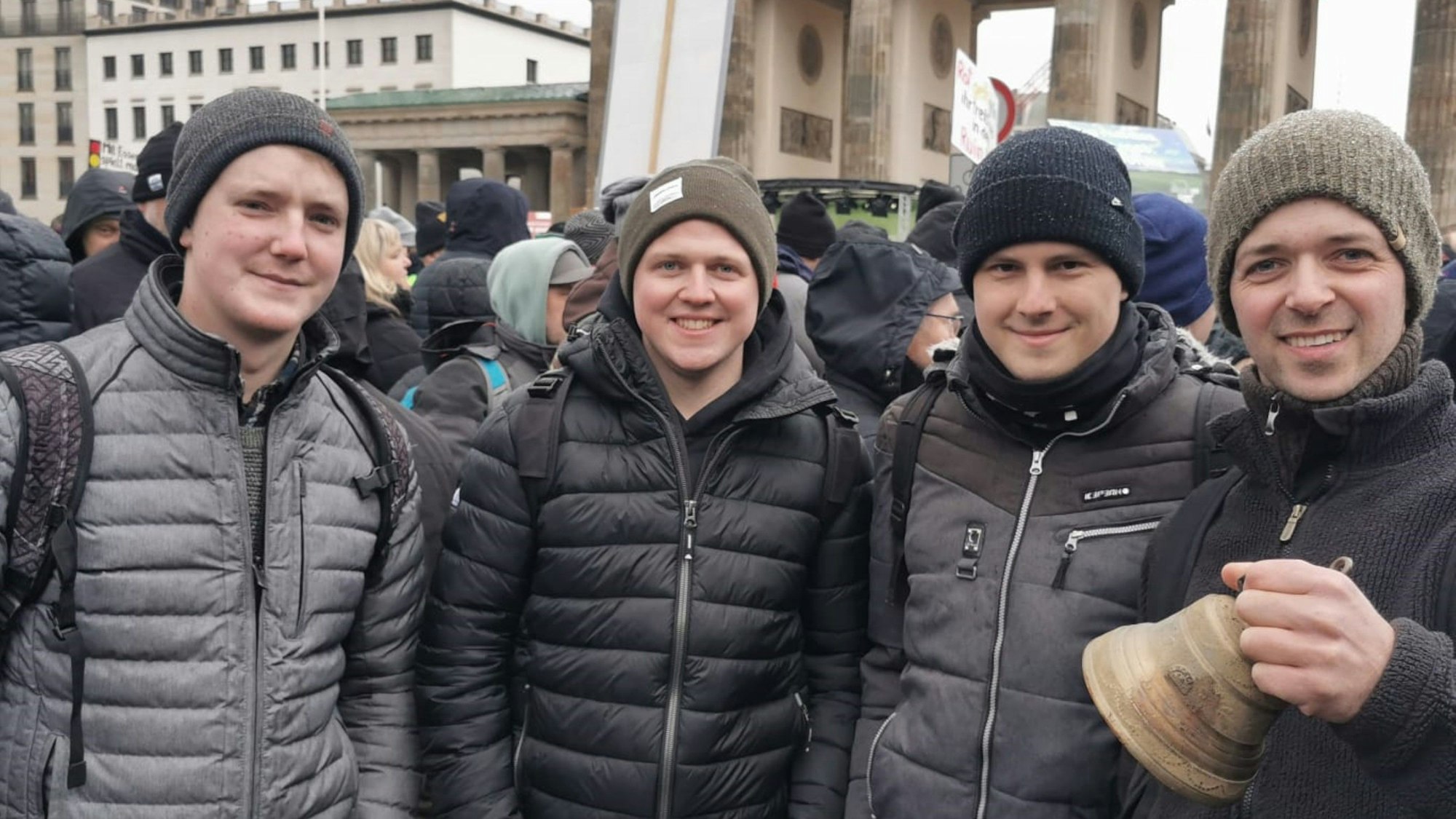 Vier junge Männer stehen vor dem Brandenburger Tor in Berlin.
