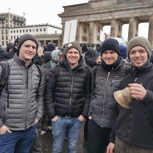 Vier junge Männer stehen vor dem Brandenburger Tor in Berlin.&nbsp;